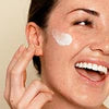 Person applying cream to face with a focus on skincare